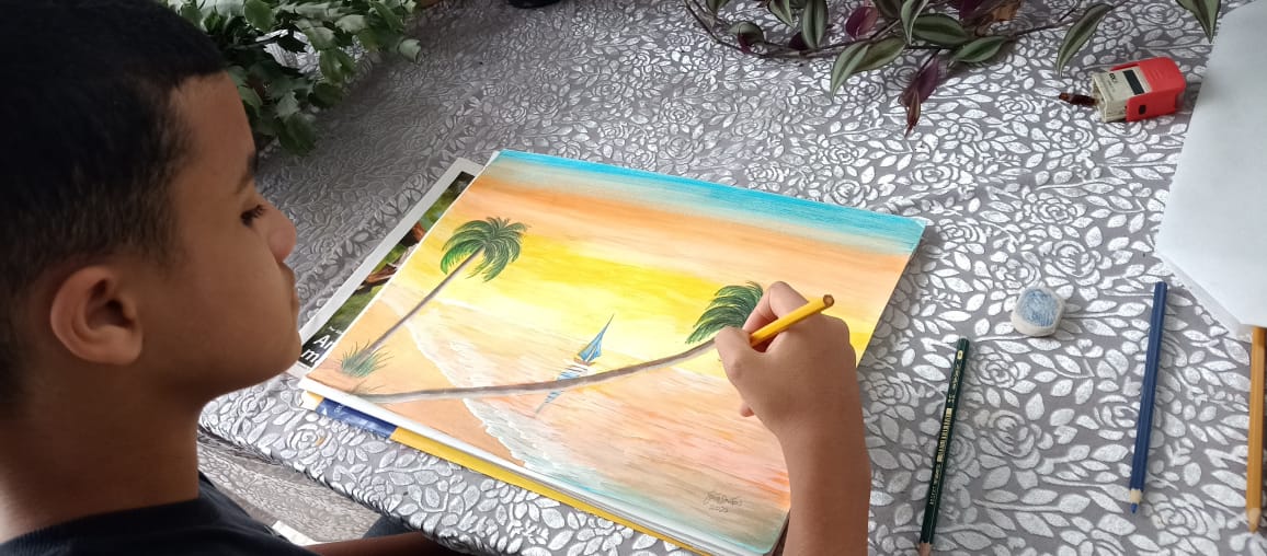 Aluno pintando paisagem de praia ao pôr do sol